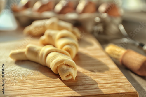 Wooden board with raw croissants, closeup © Africa Studio
