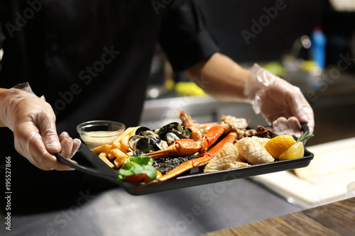 Chef with delicious seafood platter in restaurant