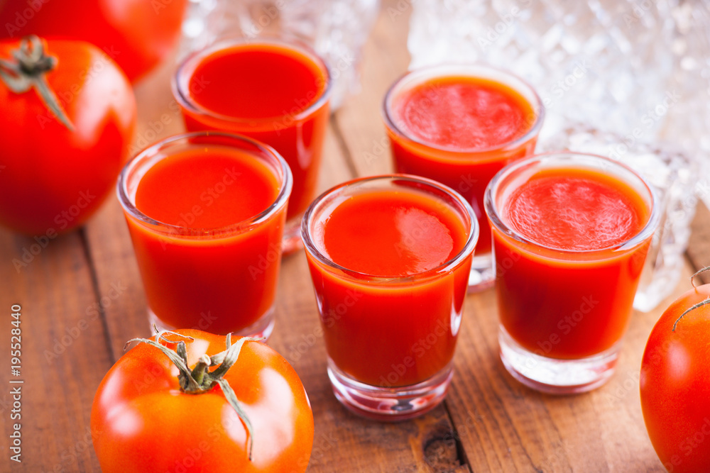 Cold Bloody Mary cocktail shot in glasses and tomatoes Cold Bloody Mary cocktail shot in glasses and tomatoes