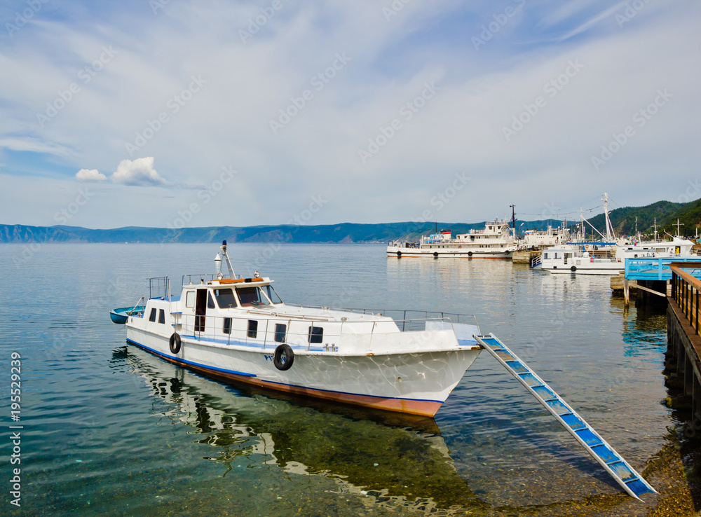 Small boat at the pier on Lake Baikal in clear turquoise waters 
