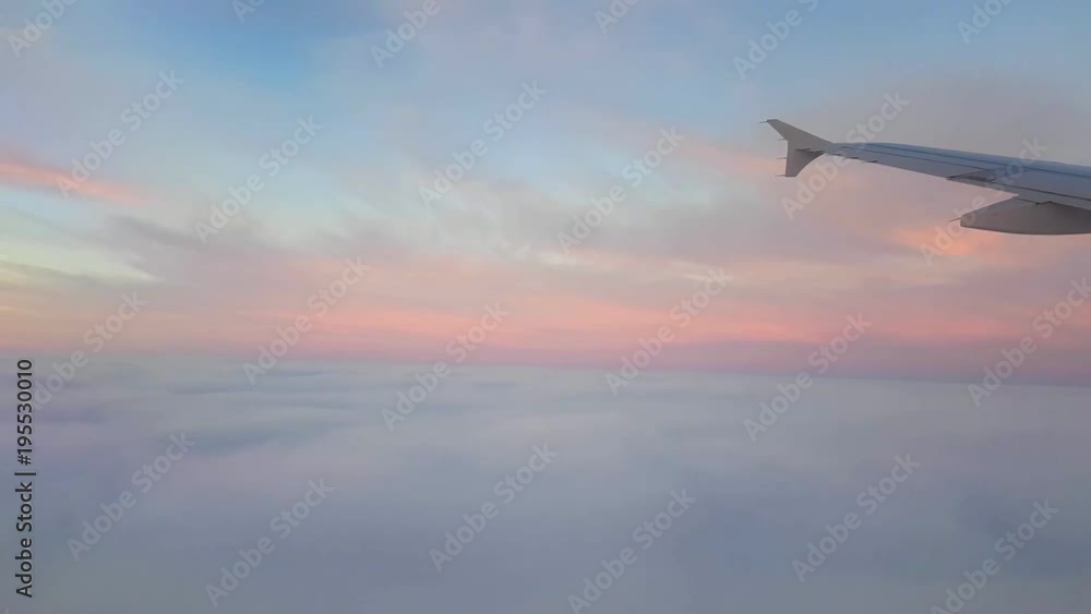 A breathtaking view from a jet airplane window flying over picturesque and sparkling pink and whiteclouds on a sunny day in summer. A breathtaking view from a jet airplane window flying over picturesque and sparkling pink and whiteclouds on a sunny day in summer.