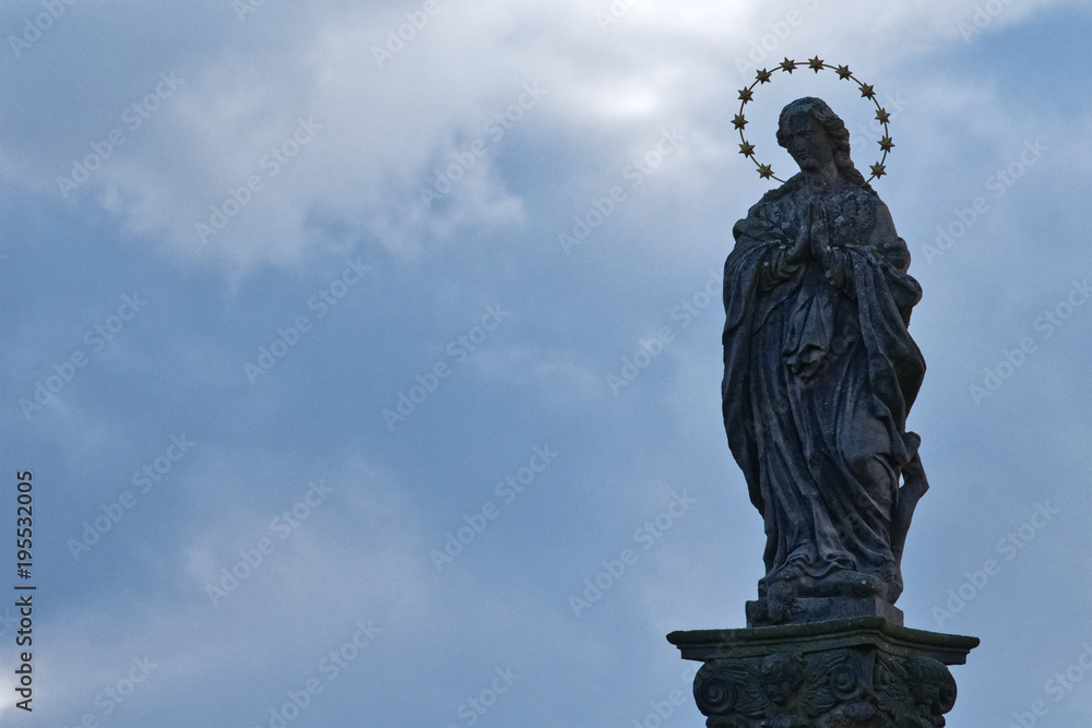 Obraz premium Statue of saint with cloudy background