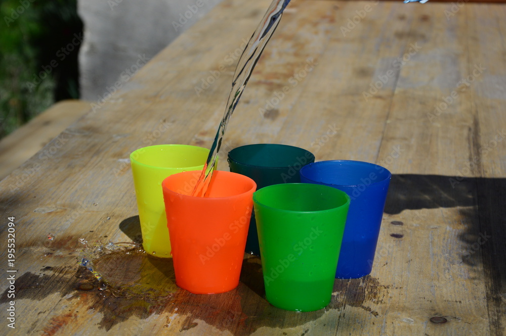 Colorful plastic cups on a wooden table, filled with water Colorful plastic cups on a wooden table, filled with water