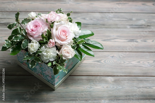 Bouquet from roses and white clove in a gift box on a wooden table
