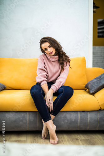 Young woman sitting on her white sofa at home