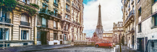 Leinwand Poster The eiffel tower in Paris from a tiny street with vintage red 2cv car