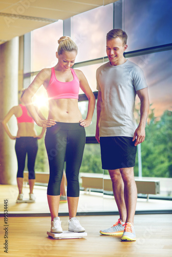 smiling man and woman with scales in gym