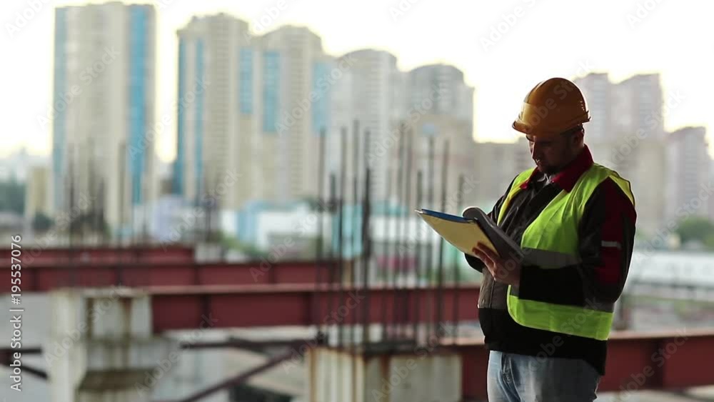 Builder works with documentations, foreman makes notes in works documentation. Workman with business papers at project site Builder works with documentations, foreman makes notes in works documentation. Workman with business papers at project site