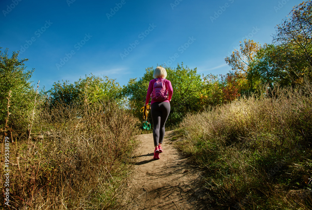 Naklejka premium Back view of sportswoman going to training in autumn park