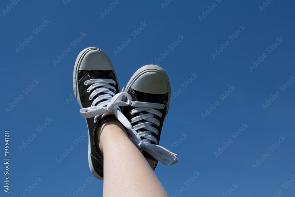A photo of a female's feet with sneakers raised up in the air with a ...