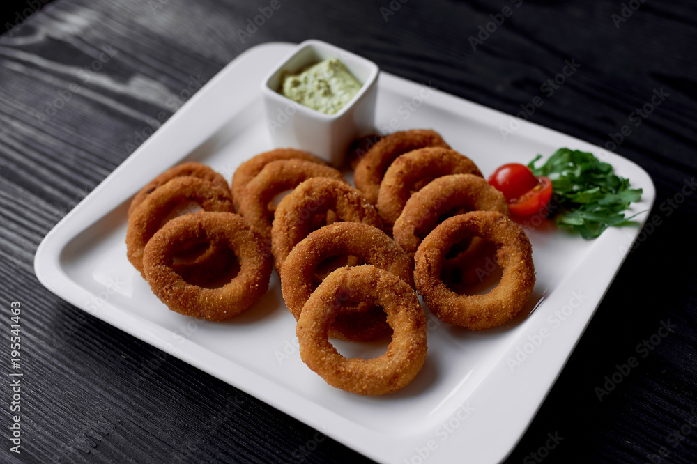 Golden onion rings fried in deep frying. With Sauce on a white plate Golden onion rings fried in deep frying. With Sauce on a white plate