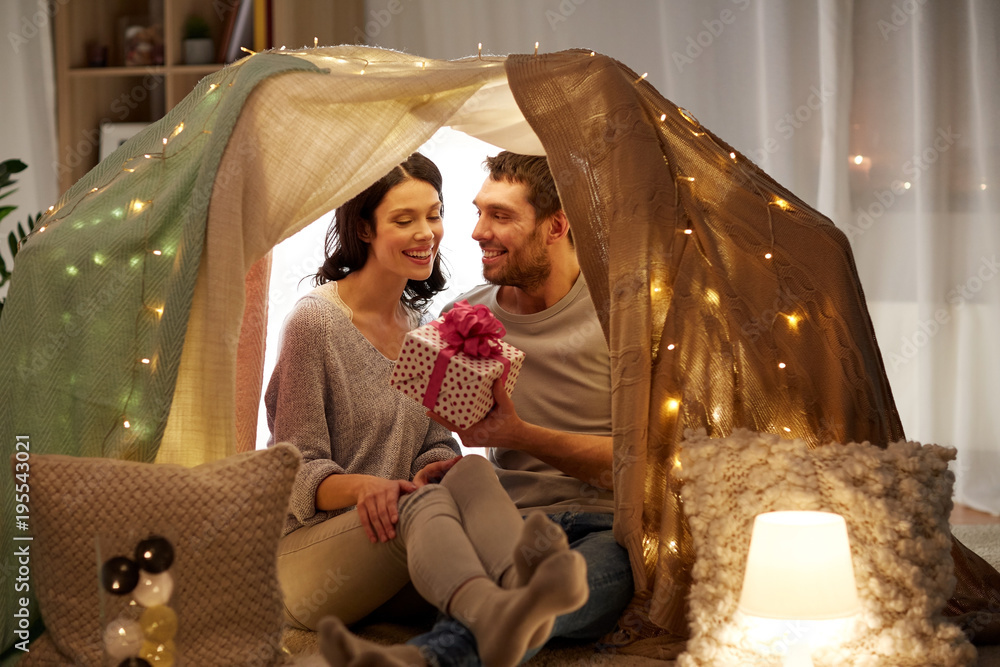 happy couple with gift box in kids tent at home