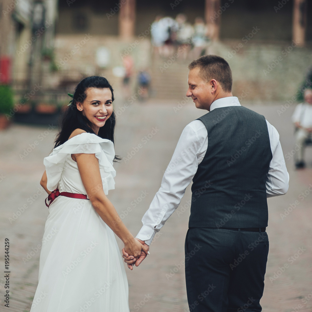 Happy bride and groom walking in an old Italian village Happy bride and groom walking in an old Italian village