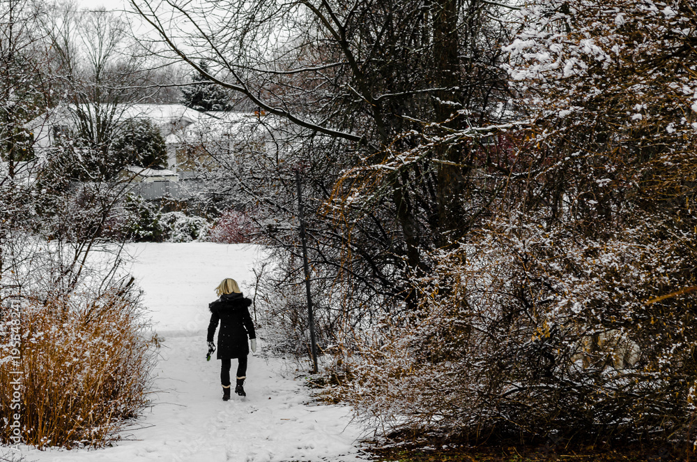 Woman walking away down a path after a fresh snowfall Woman walking away down a path after a fresh snowfall