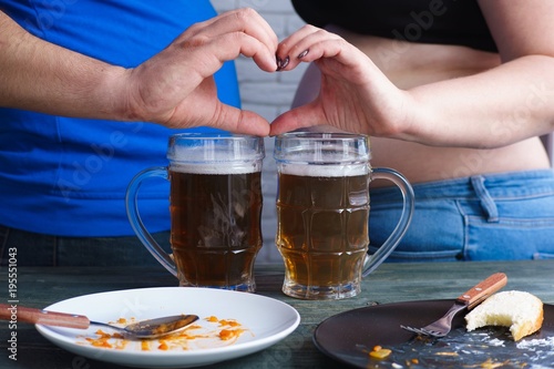 Bad habits, overeat, alcoholism concept. Overweight couple love to drink beer and eat junk food