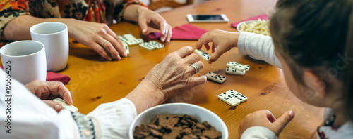 Unrecognizable grandmother, daughter and granddaughter playing domino in the living room