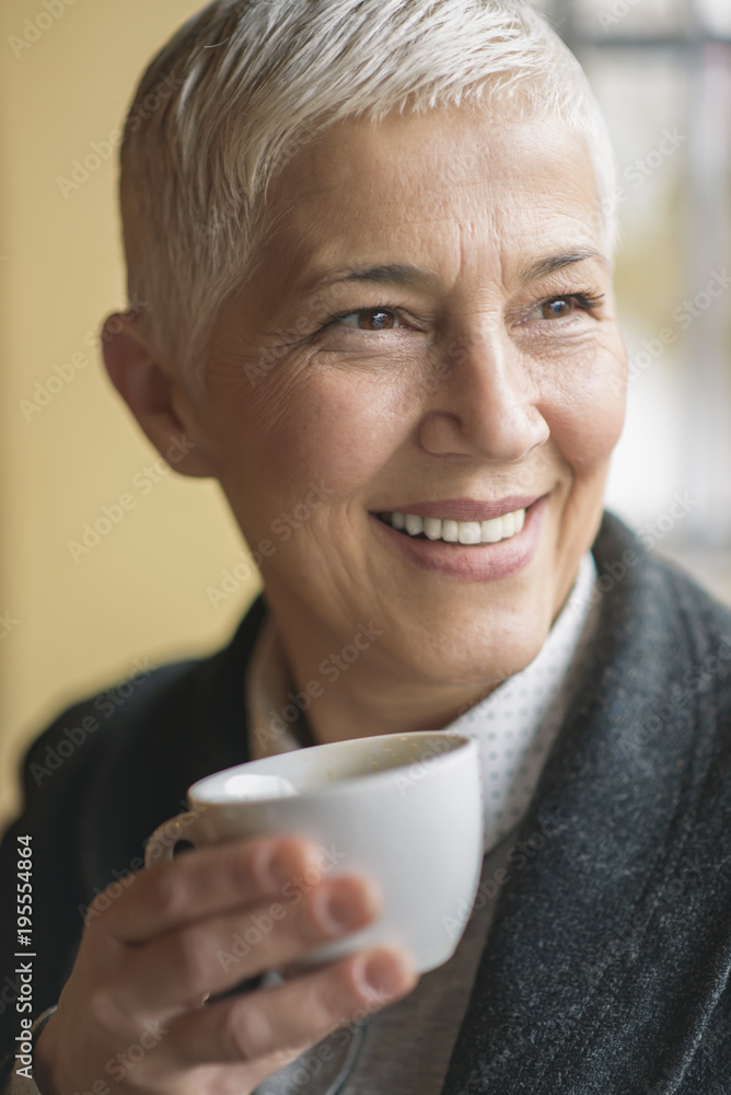 Cheerful senior woman enjoying her morning cup of coffee in a coffee shop Cheerful senior woman enjoying her morning cup of coffee in a coffee shop