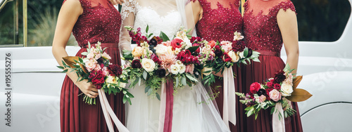 bride and bridesmaids are staying near the car with flowers