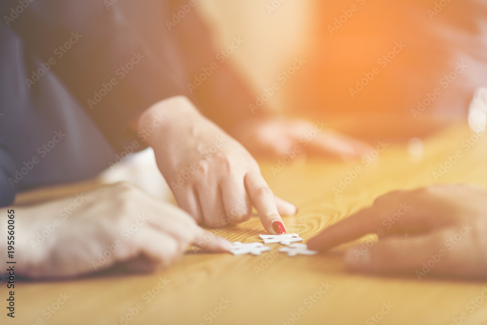 Businesspeople Hand Solving Jigsaw Puzzle On Wooden Desk, business concept Businesspeople Hand Solving Jigsaw Puzzle On Wooden Desk, business concept