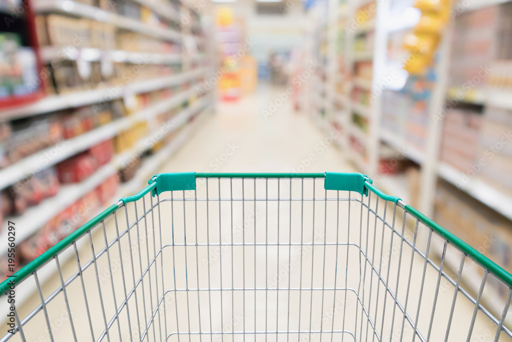 Empty shopping cart with abstract blur supermarket discount store aisle and product shelves interior defocused background