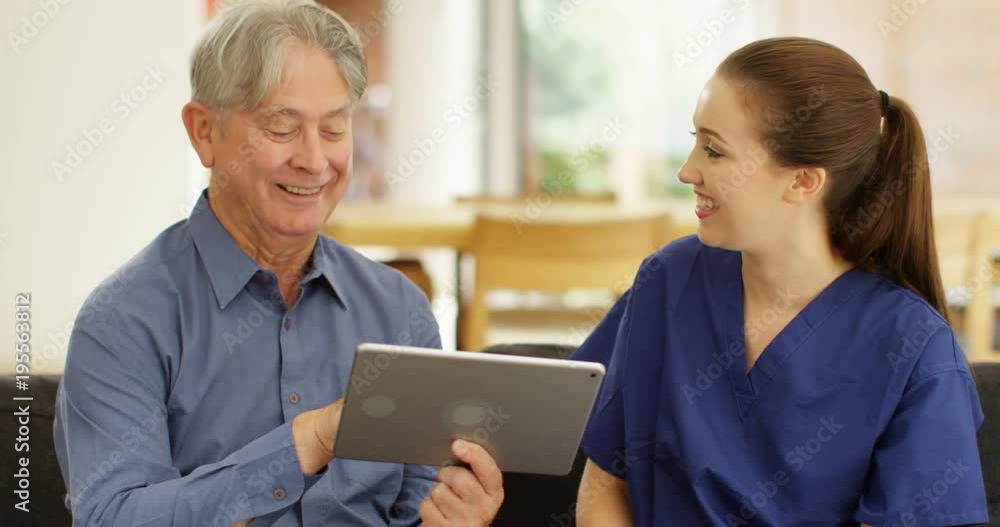 4K Cheerful home support carer teaching senior man to use computer tablet 4K Cheerful home support carer teaching senior man to use computer tablet