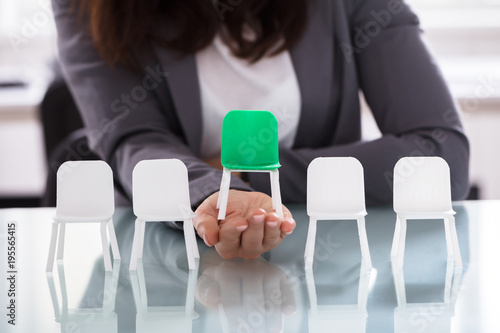 Businesswoman Choosing Green Chair Among White Chairs In A Row