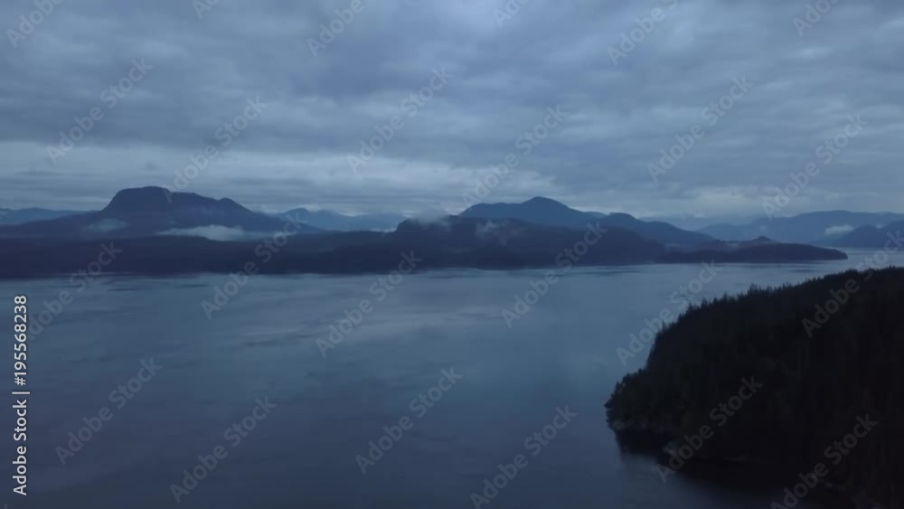 Beautiful aerial view of Johnstone Strait during a dark and cloudy sunrise during the fall season. Taken in Vancouver Island, British Columbia, Canada. Beautiful aerial view of Johnstone Strait during a dark and cloudy sunrise during the fall season. Taken in Vancouver Island, British Columbia, Canada.