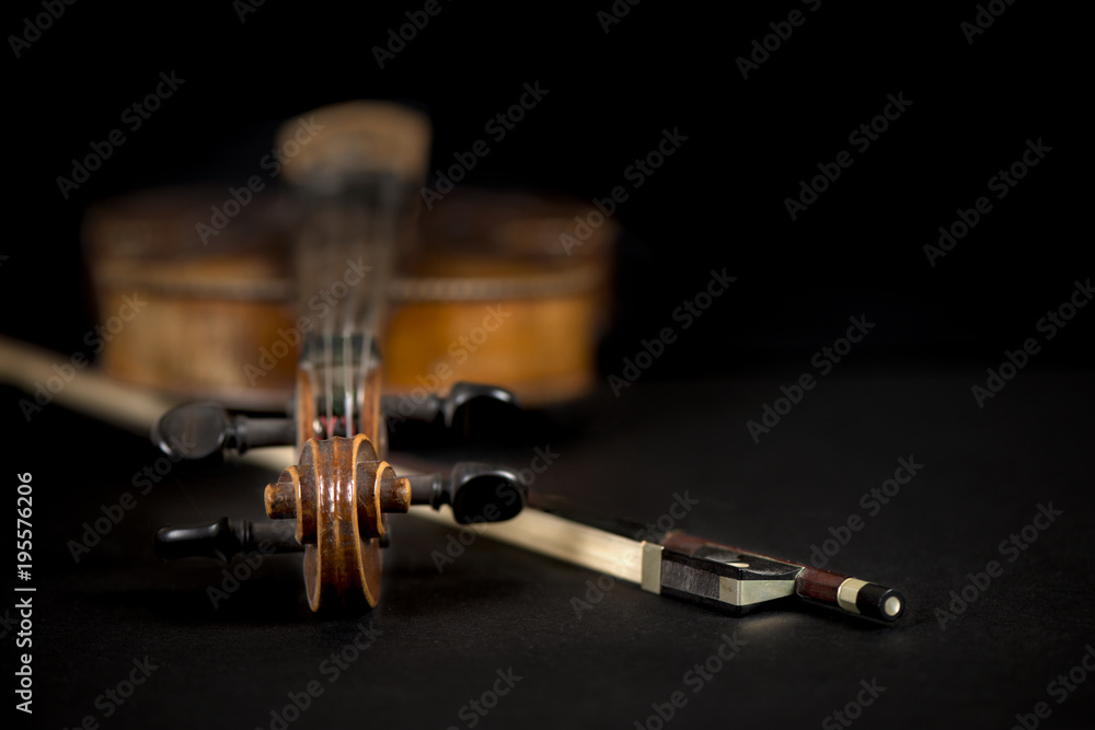 Close-up of antique, violin scroll and bow on black background