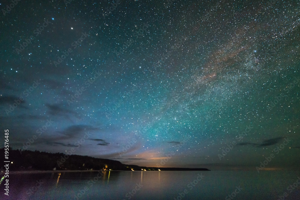 Milky Way and stars over the lake showing shoreline and cliffs at night