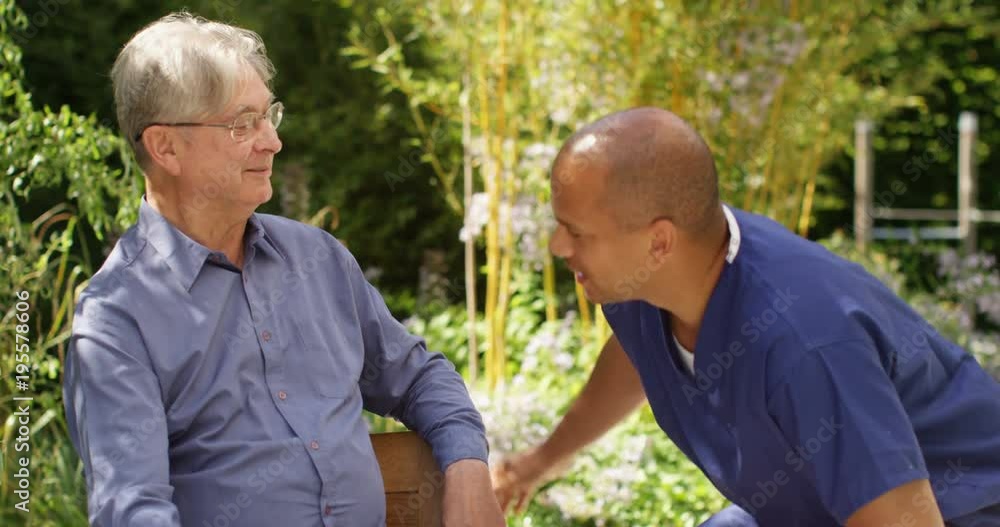 4K Cheerful senior man relaxing in nursing home garden & chatting to care assistant. Slow motion 4K Cheerful senior man relaxing in nursing home garden & chatting to care assistant. Slow motion