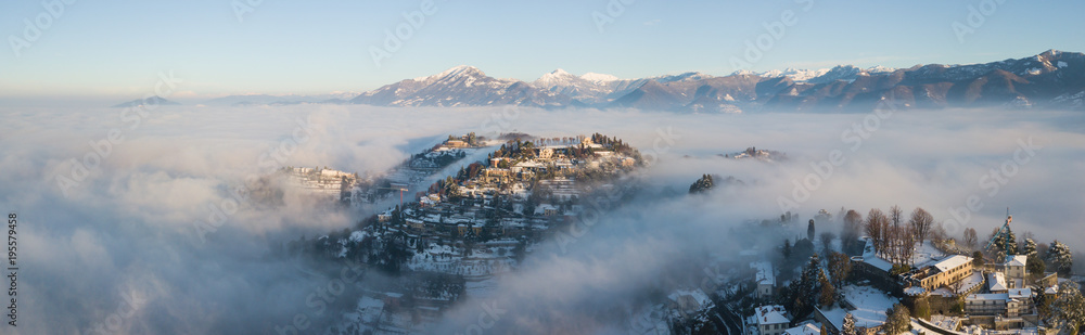 Bergamo, Italy. Drone aerial view of an amazing landscape of the fog rises from the plains and covers the hill of San Vigilio