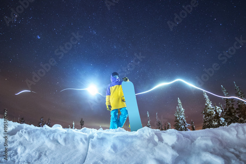 Lady snowboarder night photo against night mountains