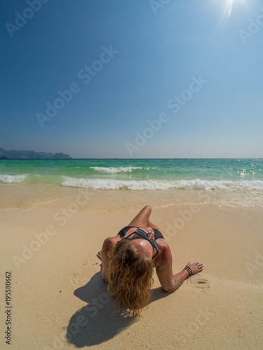 Cute woman relaxing on the summer beach. Happy lifestyle. White sand, blue sky and crystal sea of tropical beach. Vacation at Paradise. Ocean beach relax, travel to islands