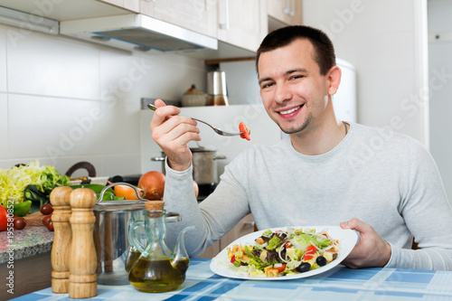 Cheerful handsome man holding plate with salad
