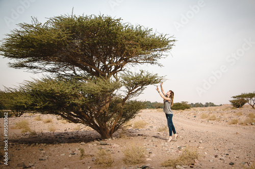 Pretty girl have fun on a tree in the desert