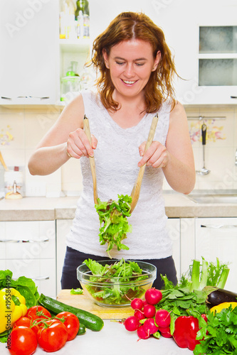 Gorgeous woman mixing a salad in her kitchen