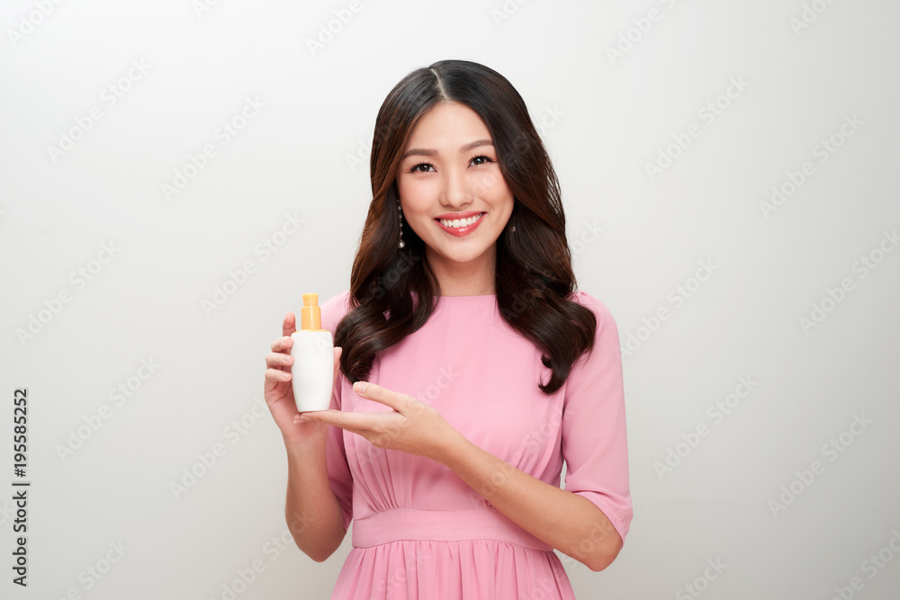 Smiling young asian woman showing skincare product. Smiling young asian woman showing skincare product.