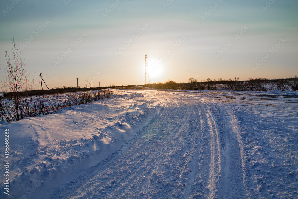 winter snowy country road with the sunset on the horizon