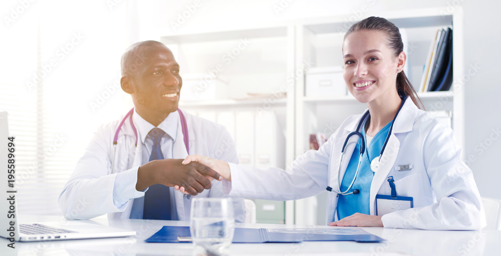 Two happy smiling young medical people handshaking at office. Doctors. Teamwork Two happy smiling young medical people handshaking at office. Doctors. Teamwork