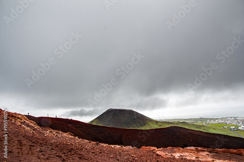 View from Eldfell of the volcanic cone of Helgafell with people walking on the edge, on Heimaey, Westman Islands, Iceland photo