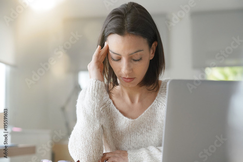 Woman working on laptop having a headache