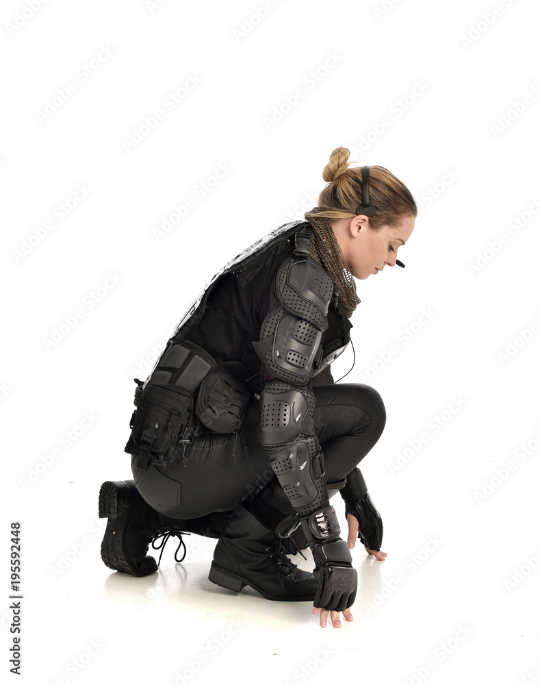 full length portrait of female soldier wearing black tactical armour, seated pose, isolated on white studio background. full length portrait of female soldier wearing black tactical armour, seated pose, isolated on white studio background.