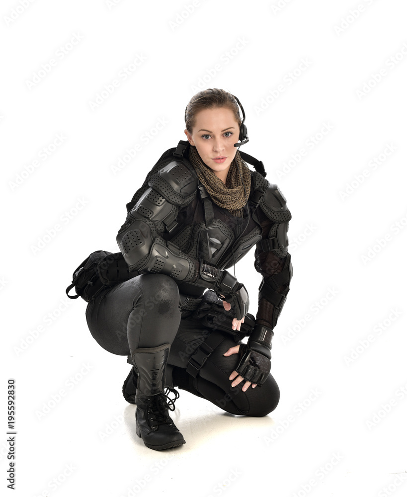 full length portrait of female soldier wearing black tactical armour, seated pose, isolated on white studio background. full length portrait of female soldier wearing black tactical armour, seated pose, isolated on white studio background.