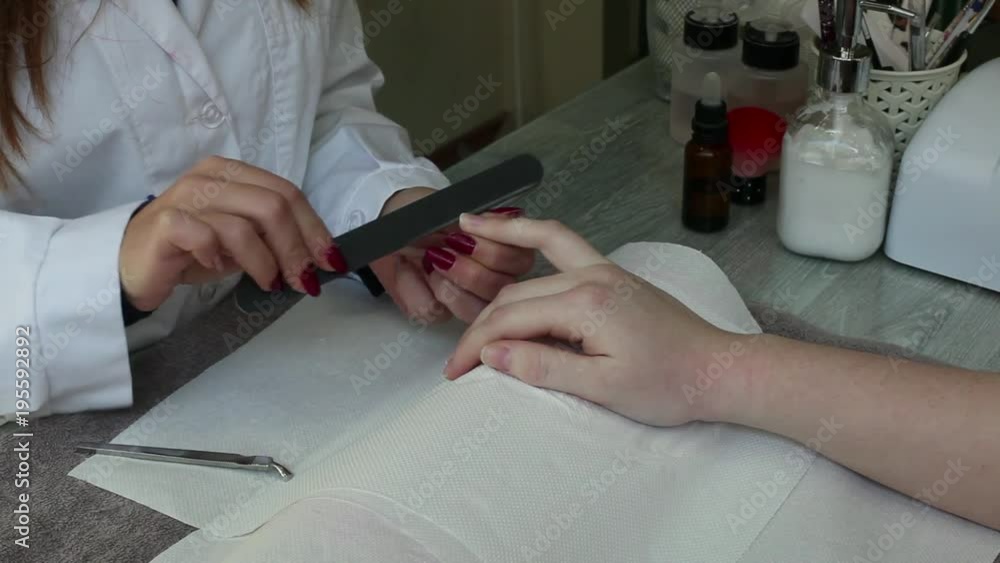 Finger nail care by manicurist to a girl client at beauty salon.