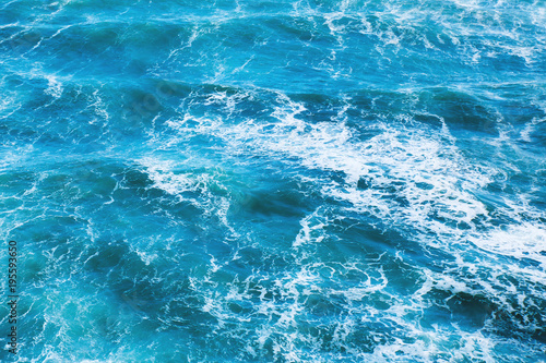 Blue sea water with waves and white foam for background.