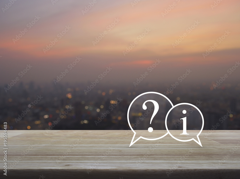 Question mark and information chat icon on wooden table over blur of cityscape on warm light sundown, Customer support concept