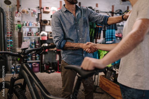 Sports shop owner selling bicycle to customer photo