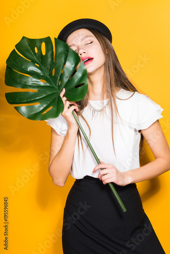a dazed woman in a hat holds a green leaf in her hands, rest