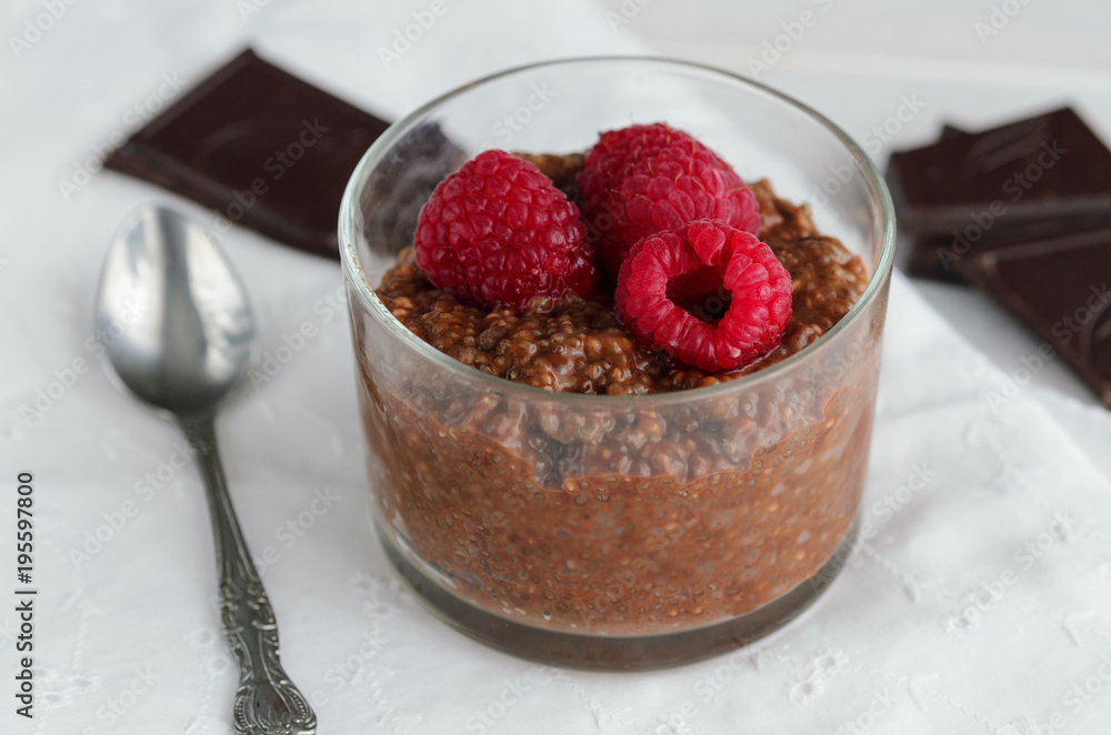 Delicious Chia chocolate pudding with almond milk and raspberries in glass on wooden table. Raw Vegan dessert background. Superfoods and healthy eating concept. Delicious Chia chocolate pudding with almond milk and raspberries in glass on wooden table. Raw Vegan dessert background. Superfoods and healthy eating concept.