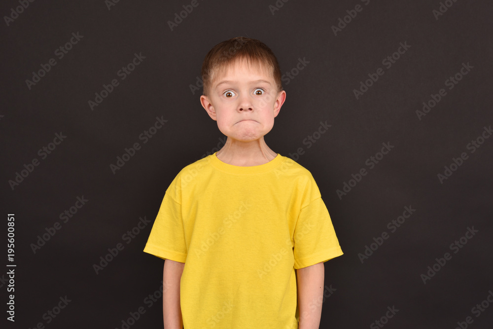Emotional guy. Portrait of a boy in a T-shirt. Shooting in the studio. A young man on a black background. Emotional guy. Portrait of a boy in a T-shirt. Shooting in the studio. A young man on a black background.